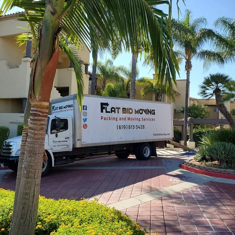 Flat Bid Moving LLC truck parked near an upscale condominium complex surrounded by palm trees.