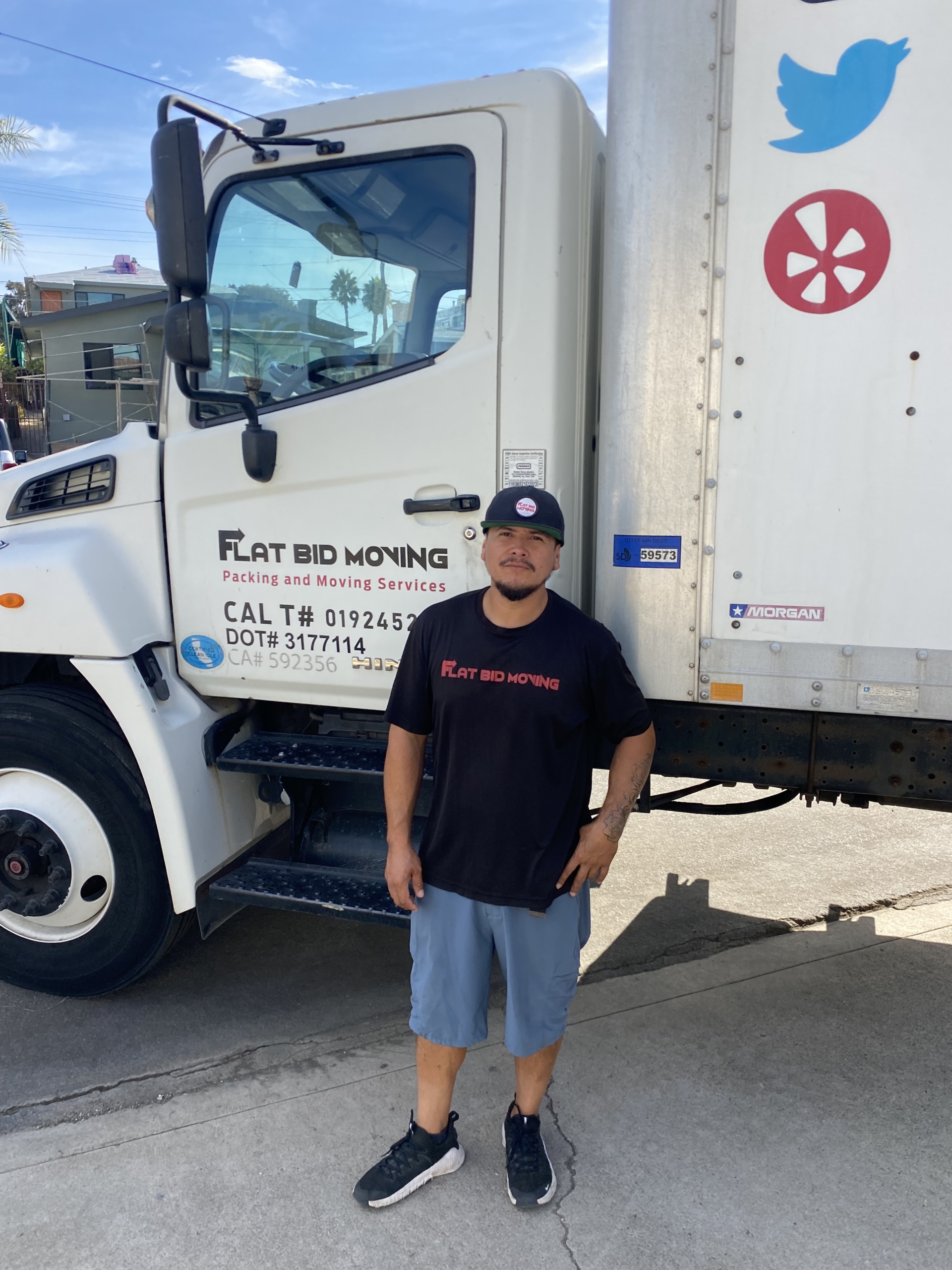 Flat Bid Moving LLC mover standing next to a large moving truck with company branding visible on the door.